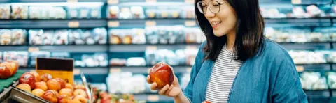 Woman picking apples in a grocery store